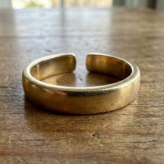 Un anillo plateado con dos filas de diamantes y un anillo de oro amarillo con un adorno esférico, sobre una roca.