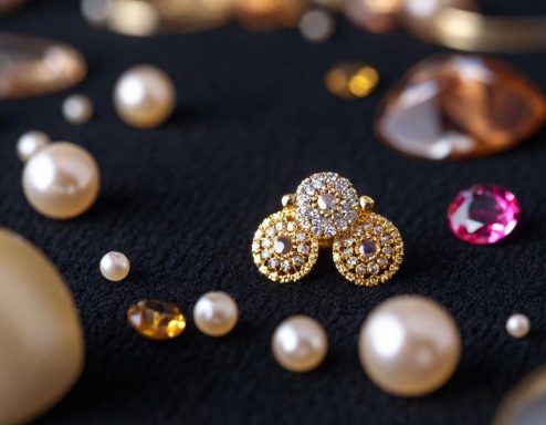 Pendientes dorados con piedras brillantes rodeados de perlas y gemas sobre fondo negro.