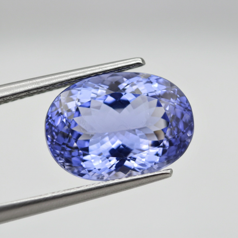 Gema de tanzanita de talla ovalada, de color violeta-azul intenso, sostenida por pinzas.